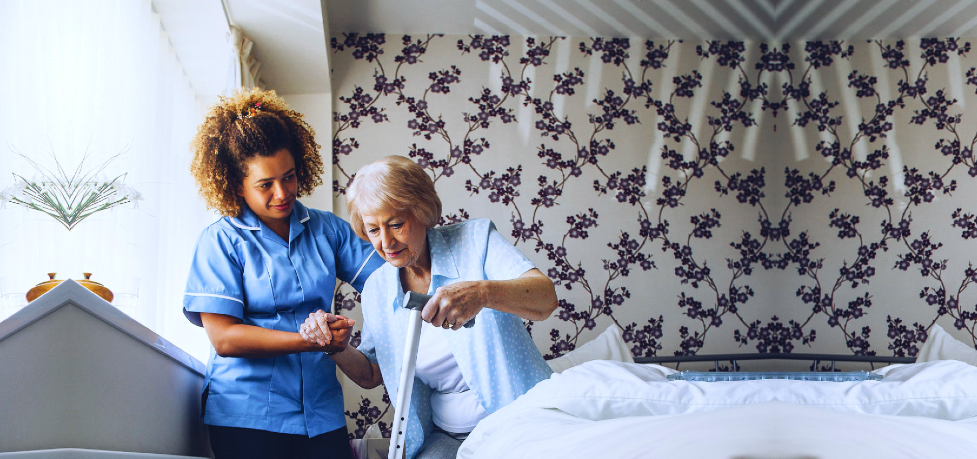 caregiver assisting senior woman holding her walking stick