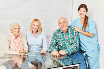 senior couple with adult woman and caregiver smiling